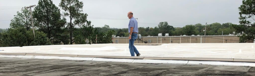 Commercial roofing professional inspecting a flat roof to determine whether it qualifies for restoration