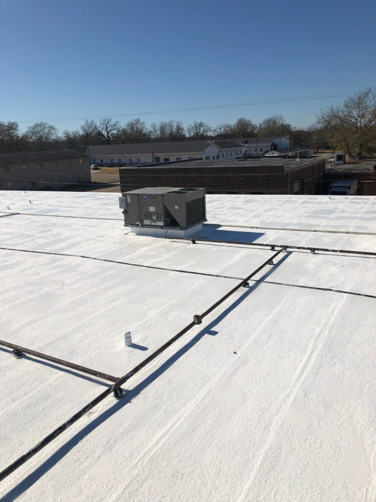 Completed commercial roof restoration with white fluid-applied roof coating in Arkansas