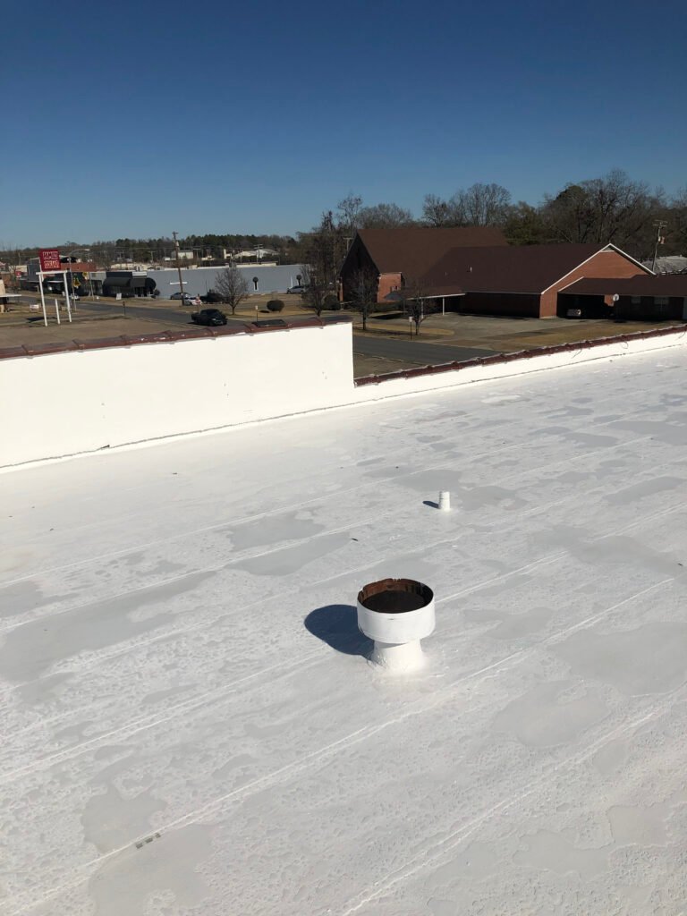 Restored commercial flat roof with white protective coating system in Arkansas