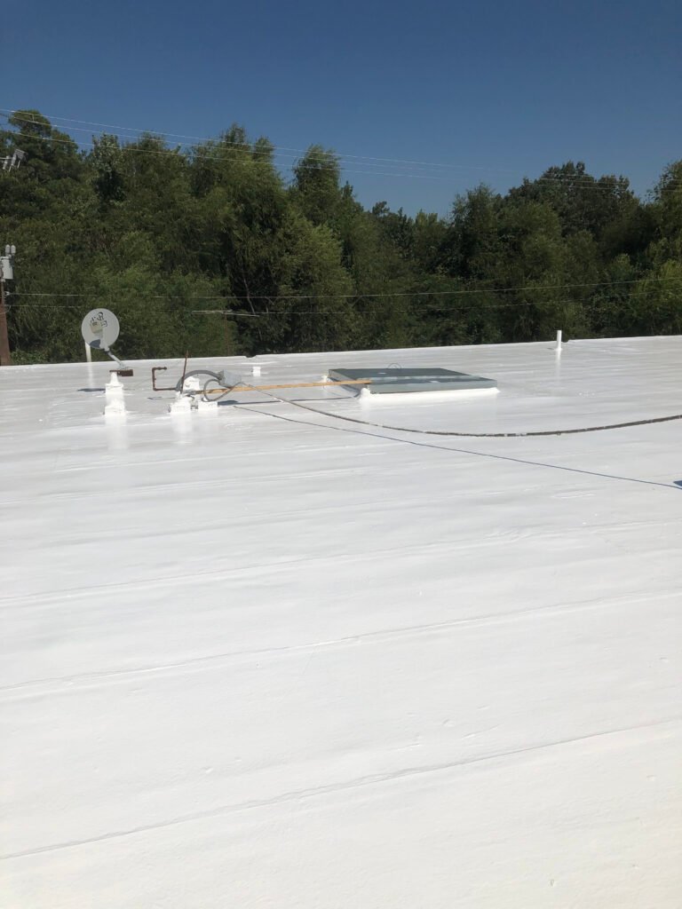 Restored commercial roof with seamless white protective coating in Arkansas