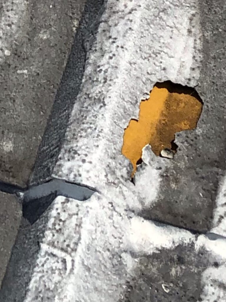 Deteriorated commercial metal roof with exposed corrosion before restoration