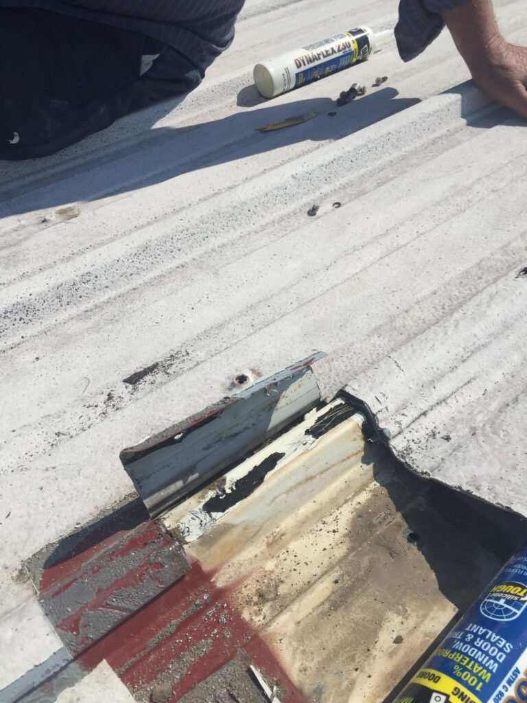 Damaged commercial metal roof section exposed during restoration repairs
