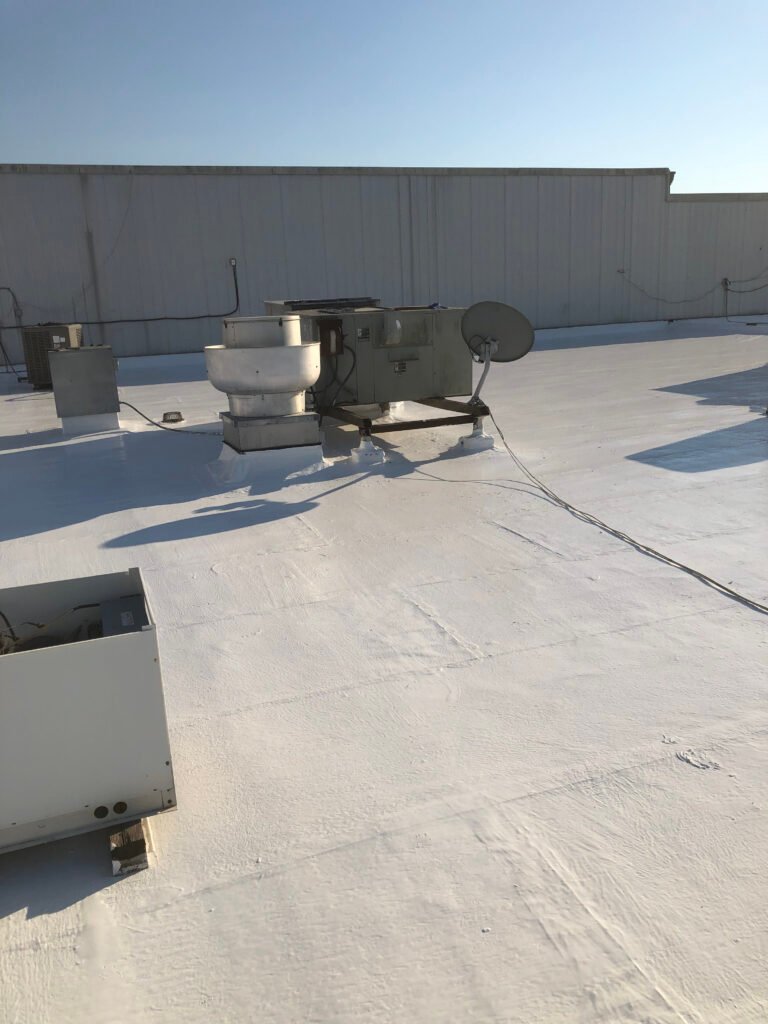 Restored commercial roof with white protective coating around rooftop HVAC equipment