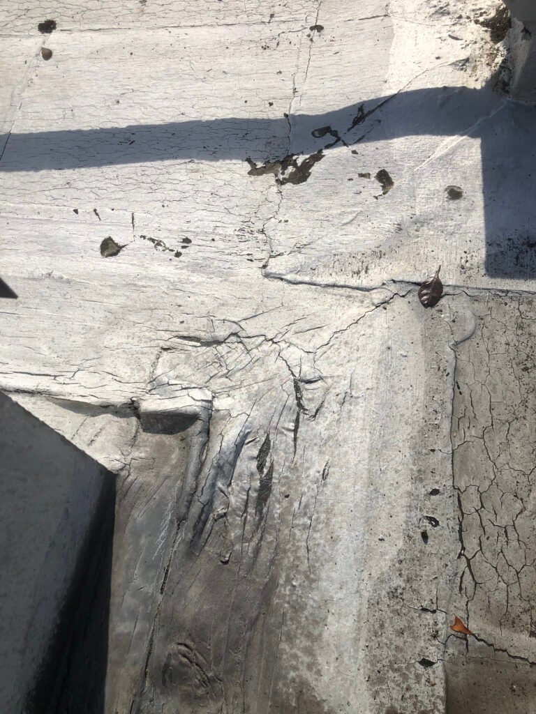 Cracked and deteriorated commercial roof coating before restoration