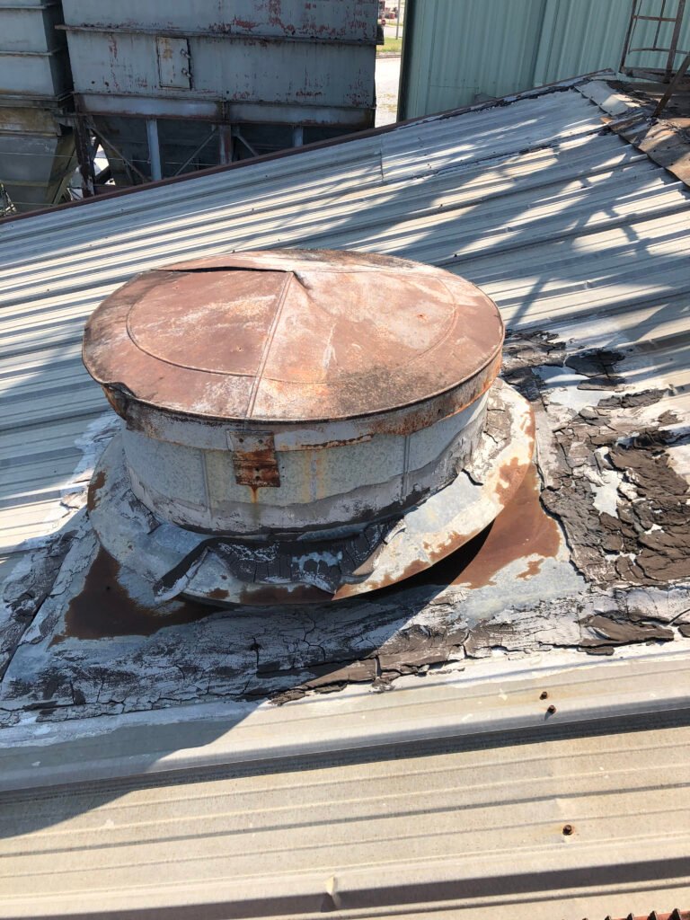 Deteriorated commercial metal roof and failed flashing around rooftop vent