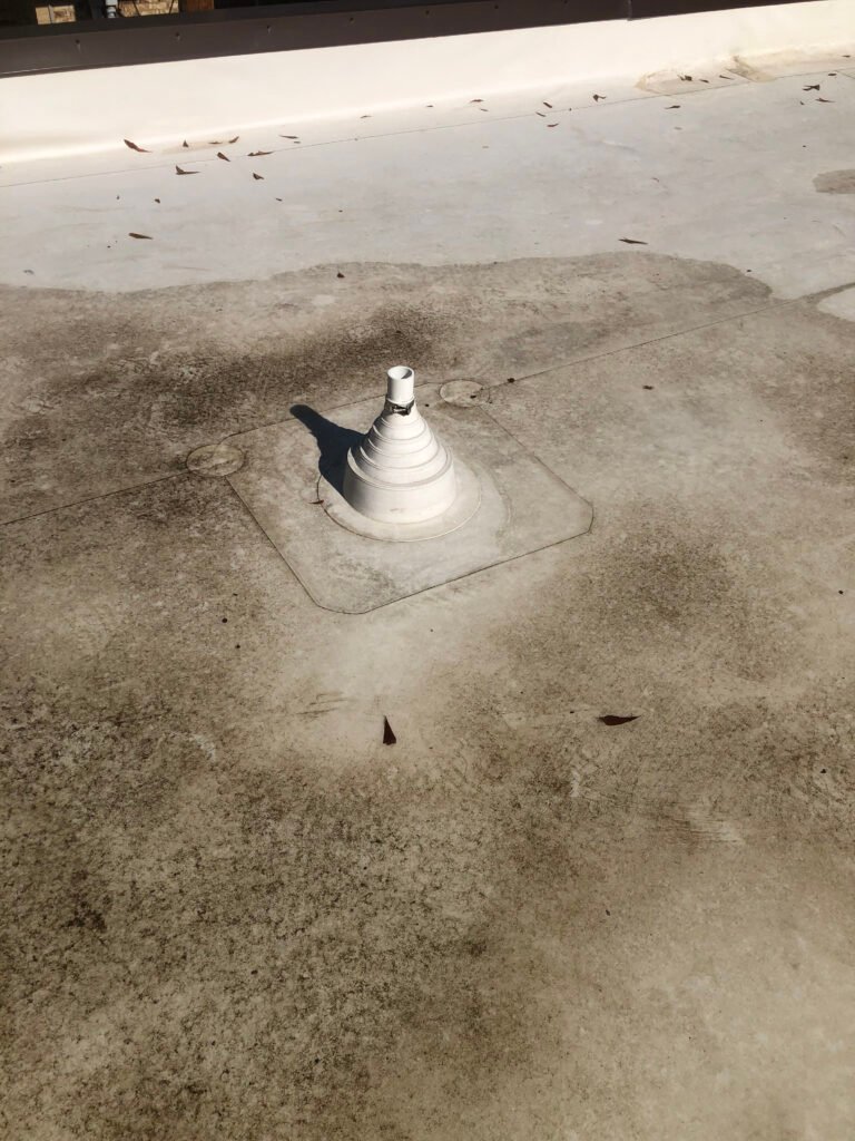 Weathered commercial roof membrane around pipe penetration before restoration