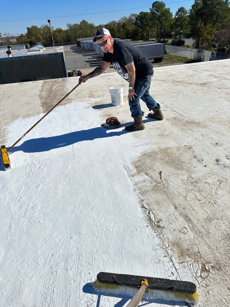 Commercial roofer applying protective roof coating during restoration