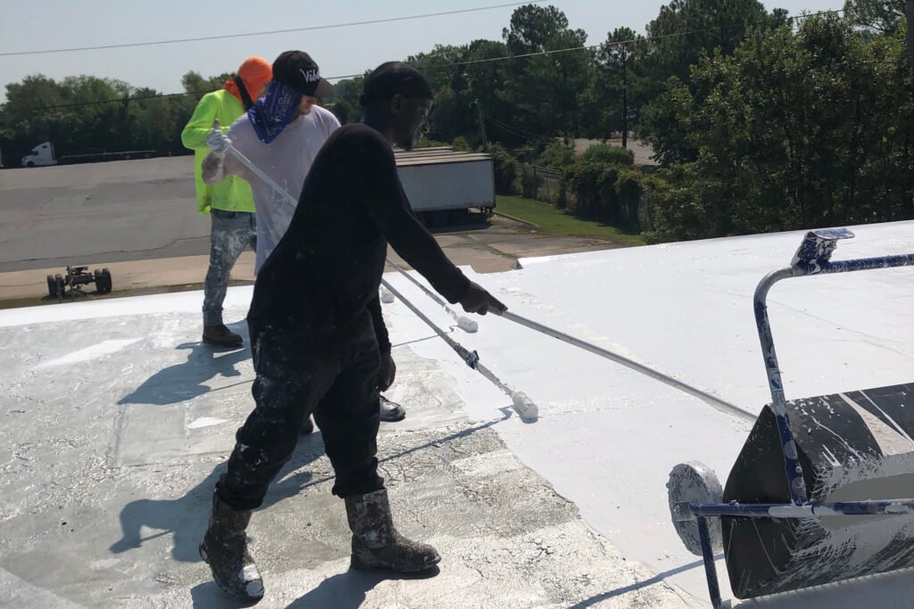 Commercial roof restoration crew applying reflective roof coating